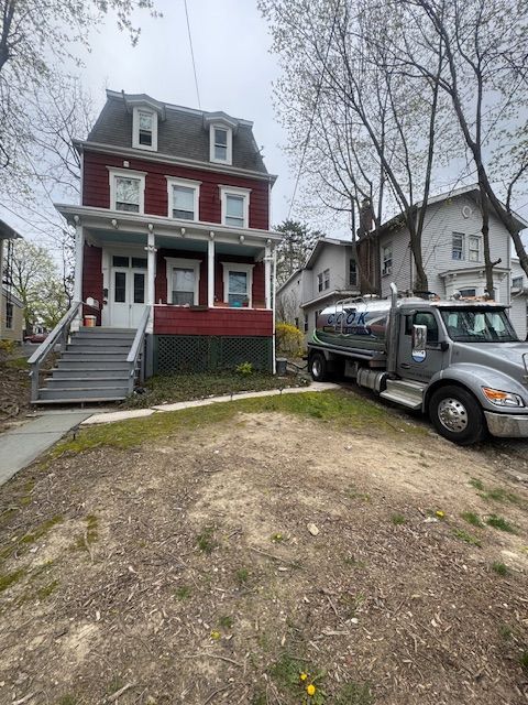 Red two-story house with oil truck parked on the side.