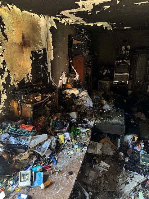 Room interior severely damaged by fire, with charred walls and debris scattered on the floor.