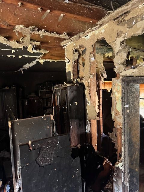 Fire-damaged interior: exposed beams, charred cabinets, and crumbling plaster.