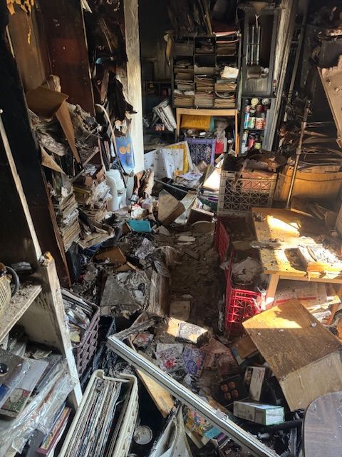 Interior room heavily damaged; debris and collapsed items block pathway.