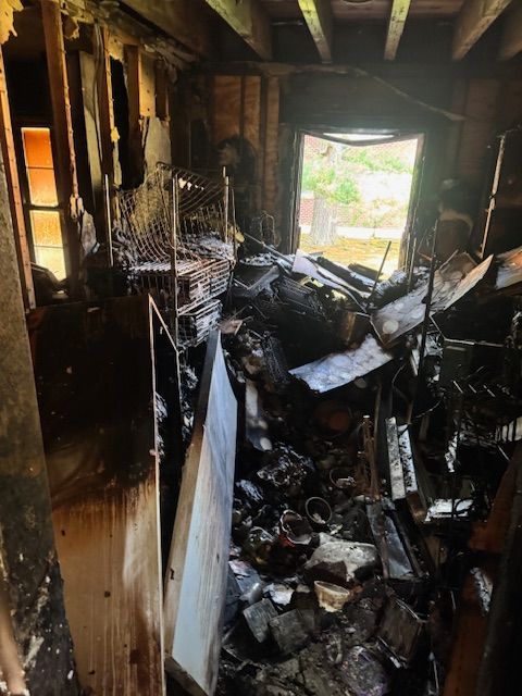 Interior room heavily damaged by fire; debris, charred wood, and a doorway.