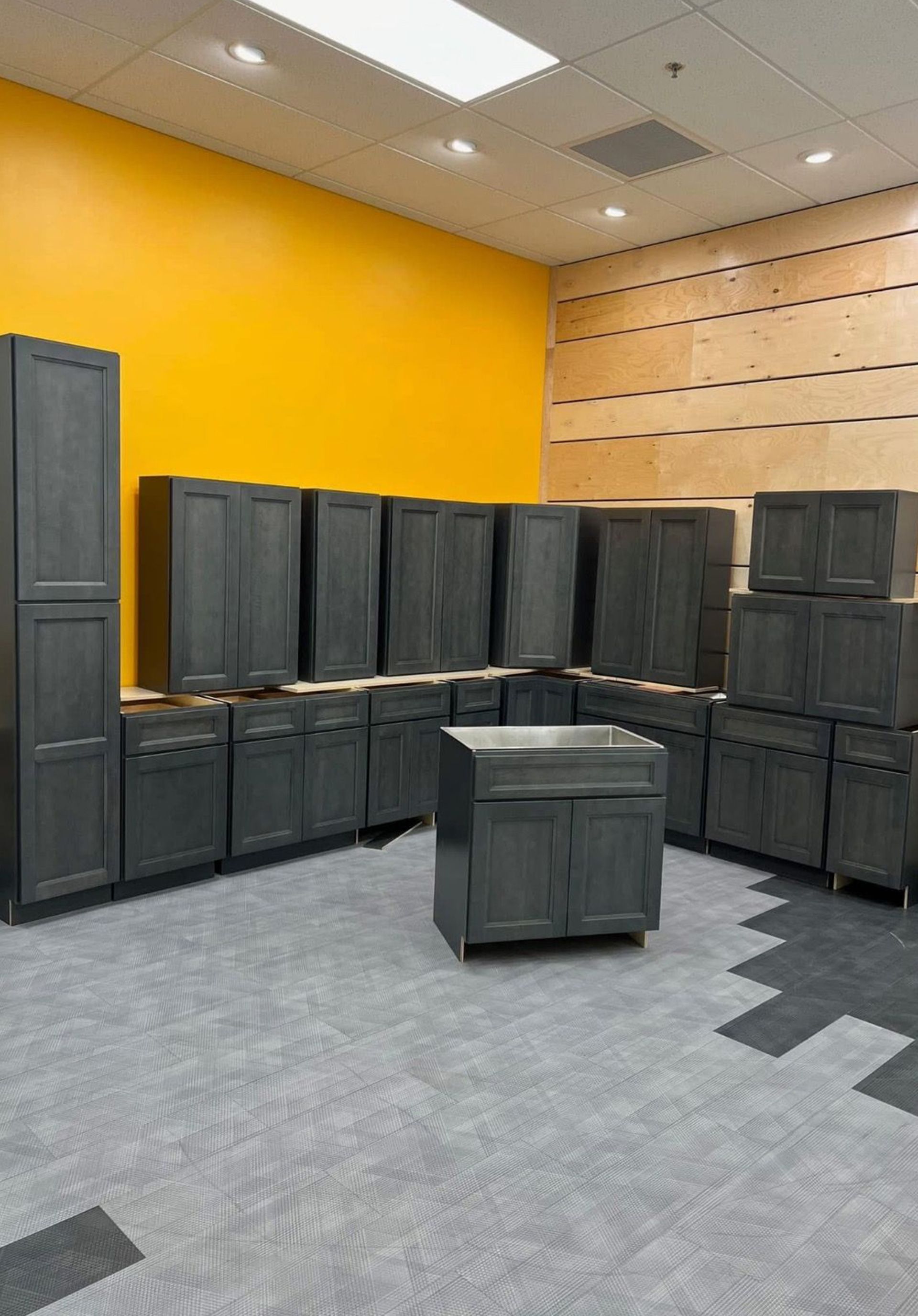 Yellow-walled room with stacked black storage bins and cabinets on gray carpet.