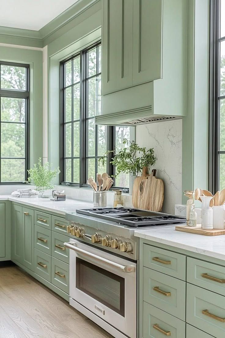 Mint-green kitchen with large windows, white countertops, and a stainless steel stove and oven