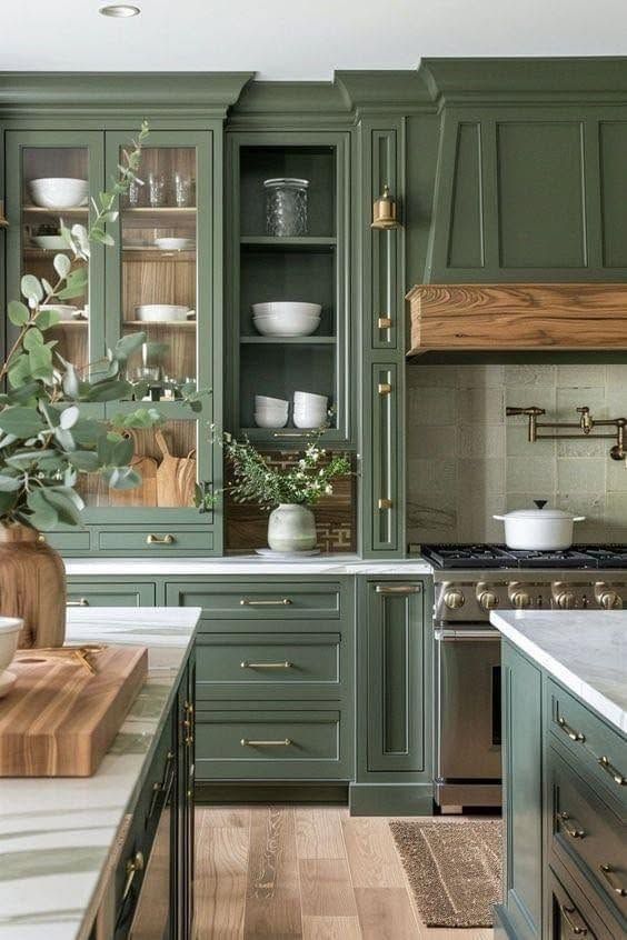 Green farmhouse kitchen with wooden countertops, open shelves, and a stove beneath a wood hood