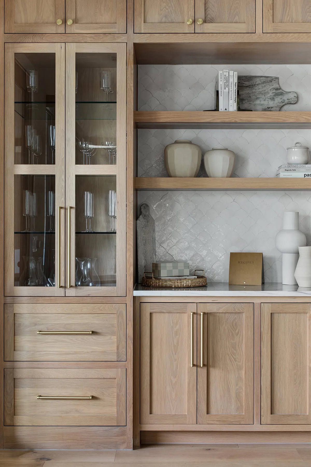 Light wood kitchen cabinets with glass-front doors, open shelves, and white ceramic decor