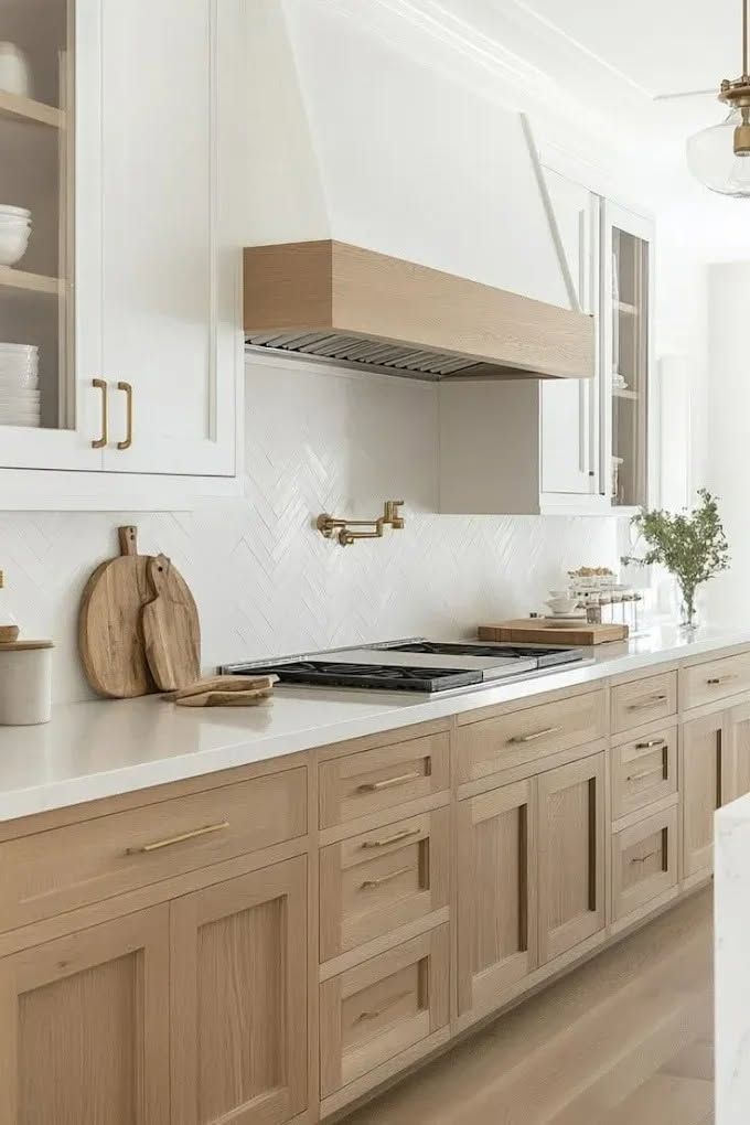 Bright modern kitchen with light wood cabinets, white walls, and a stainless range hood