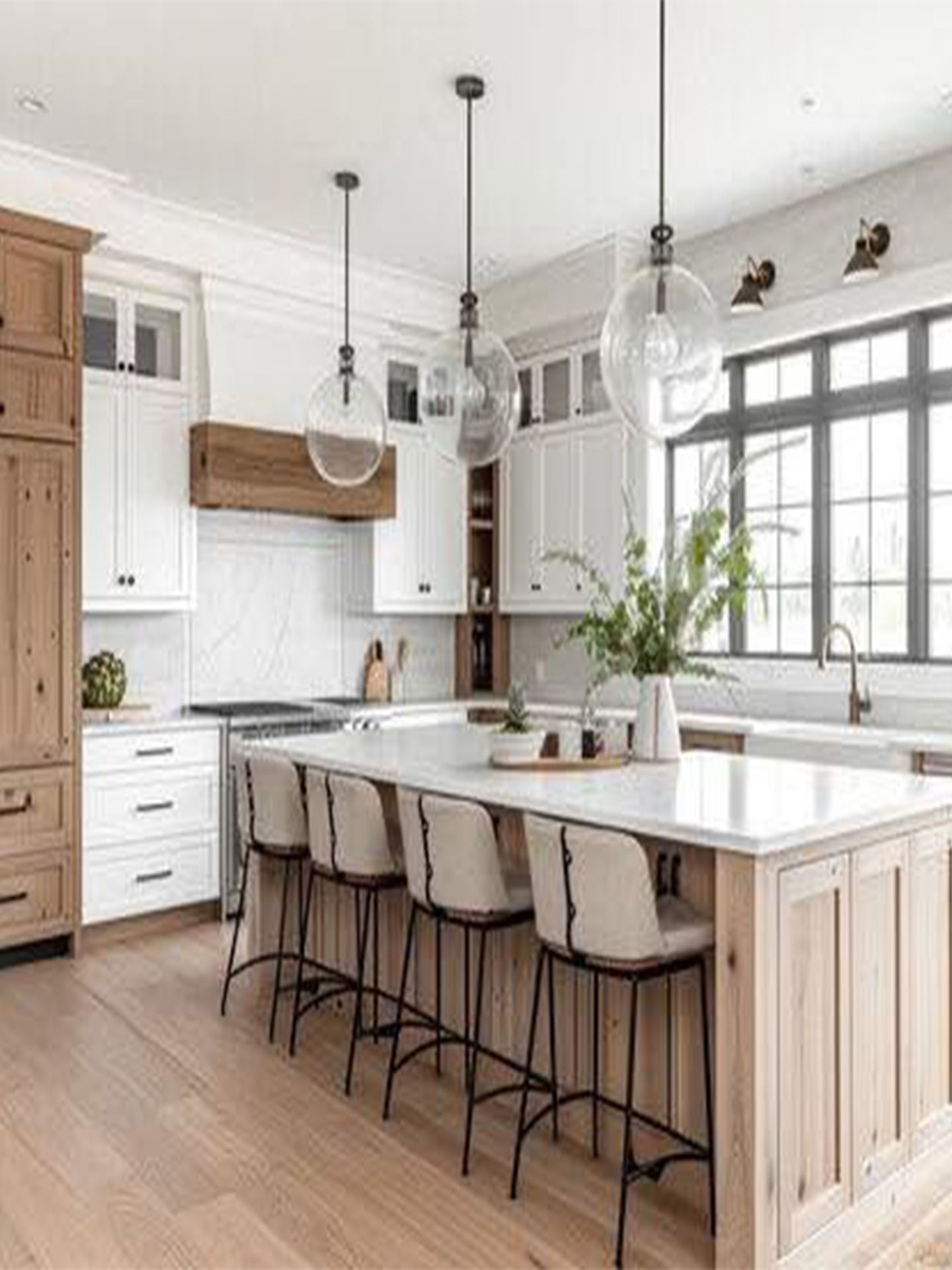 Bright modern kitchen with white cabinets, wood accents, island seating, and large windows