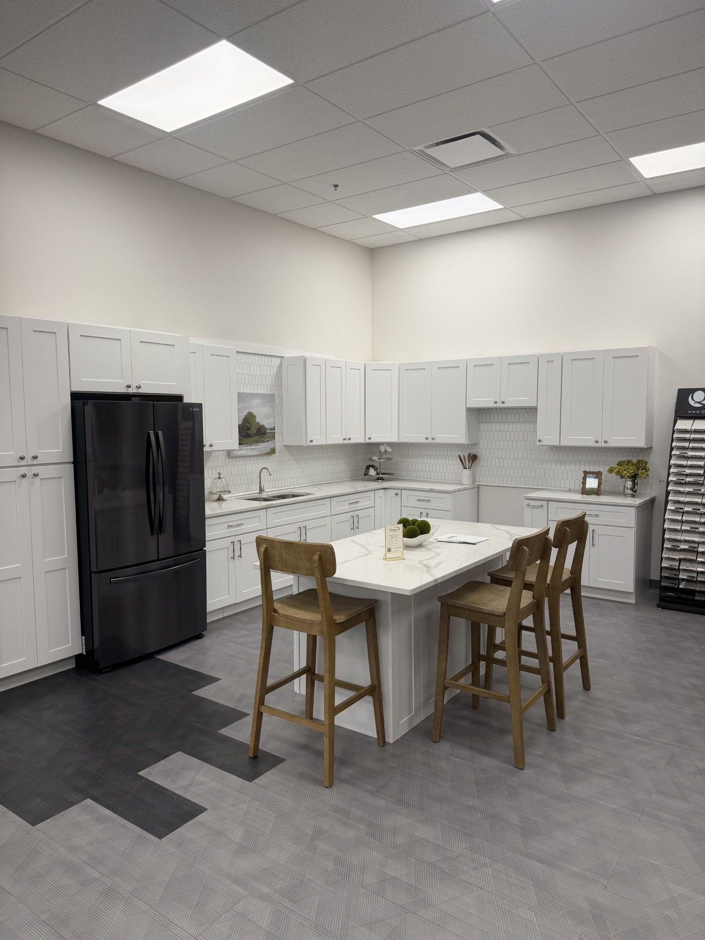 Modern kitchen with white cabinets, black fridge, and a central island with wooden stools