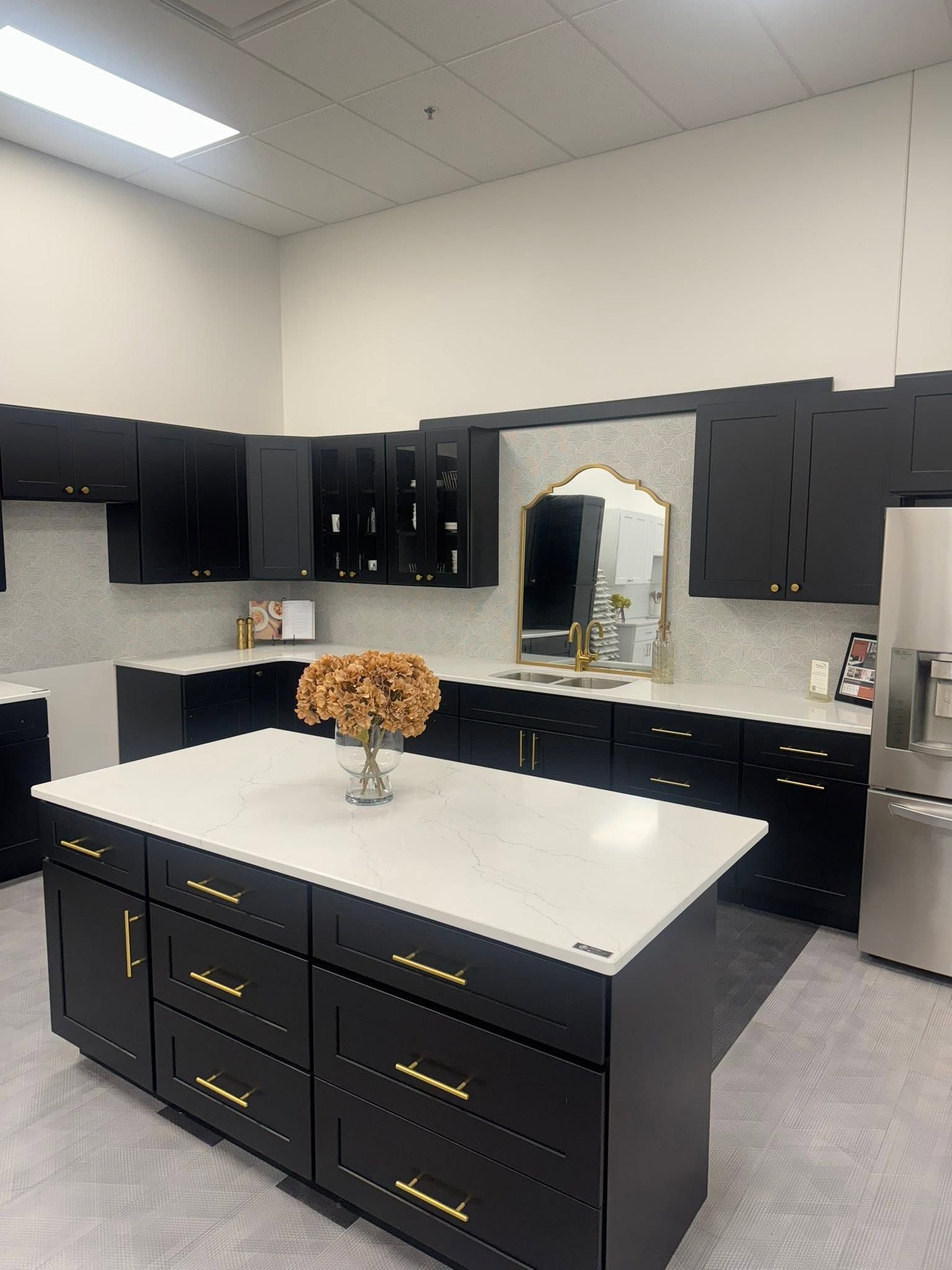 Modern black-and-white kitchen with a marble island, dark cabinets, and gold handles.