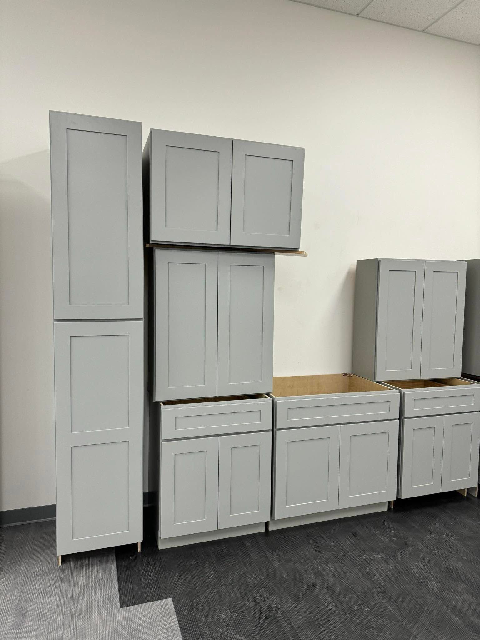 Gray cabinets stacked against a wall in a carpeted room under construction or renovation