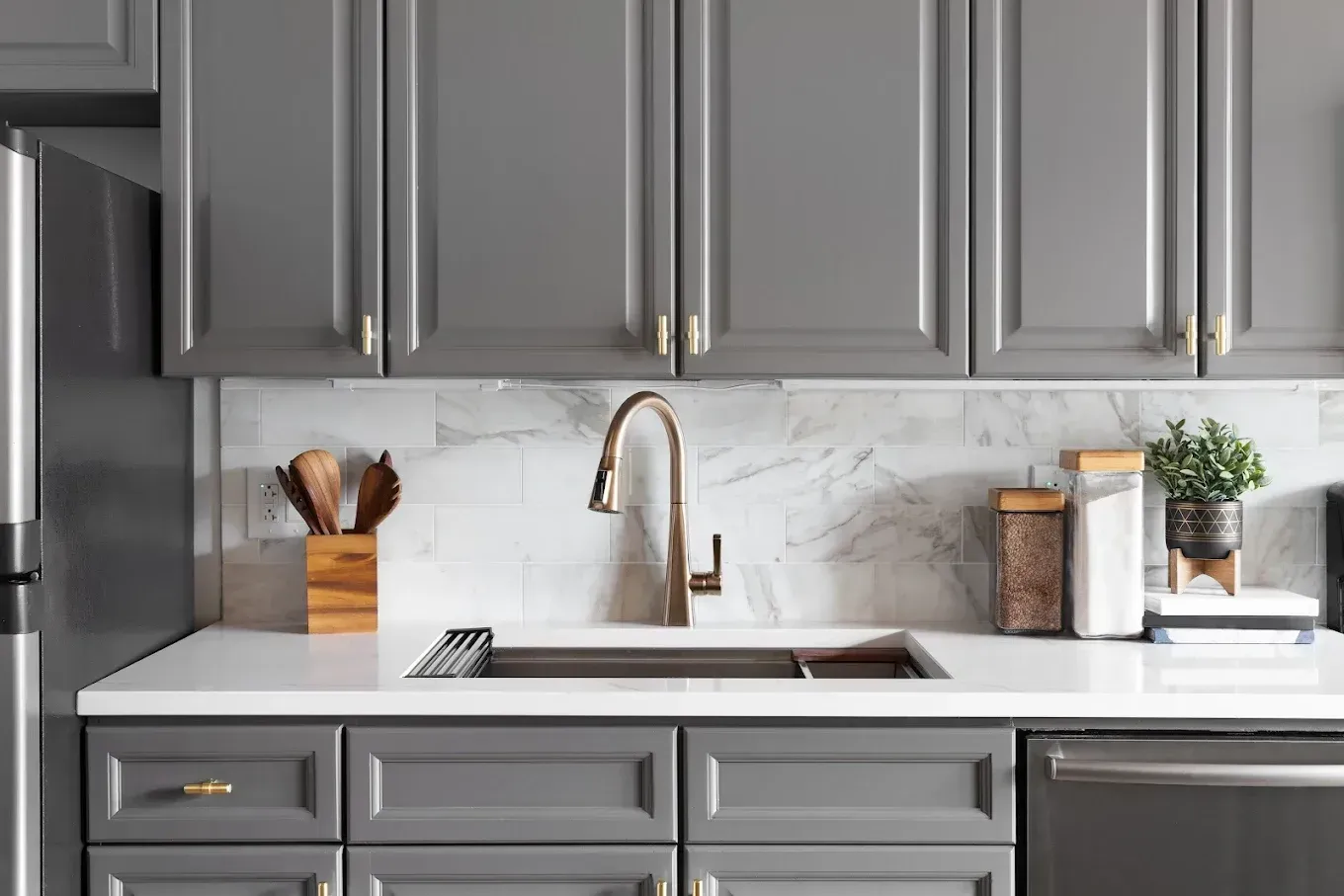 Gray and white kitchen with a sink, faucet, and cabinets.