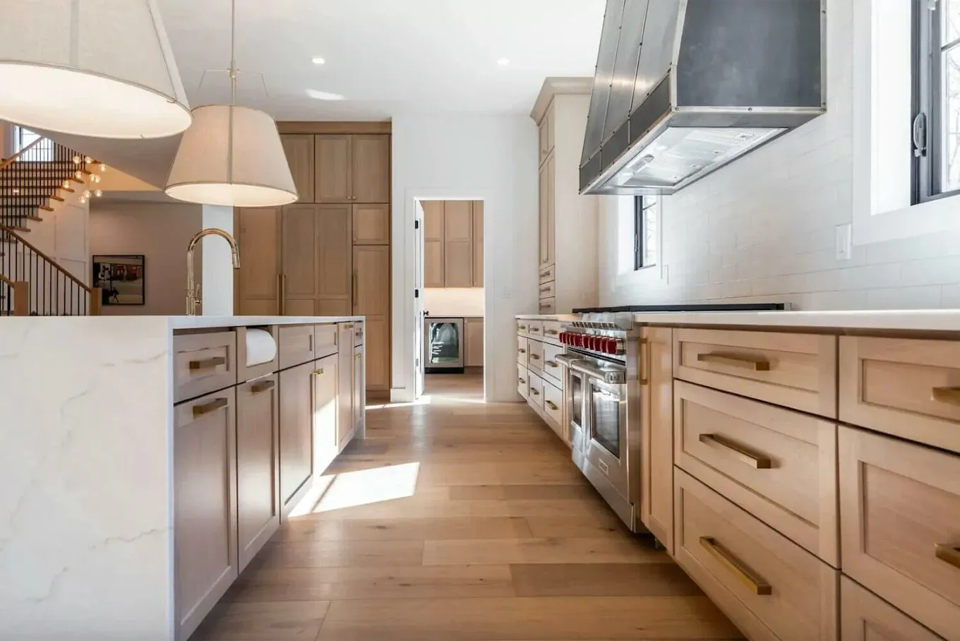 Modern kitchen with light wood cabinets, white countertops, and stainless steel appliances.