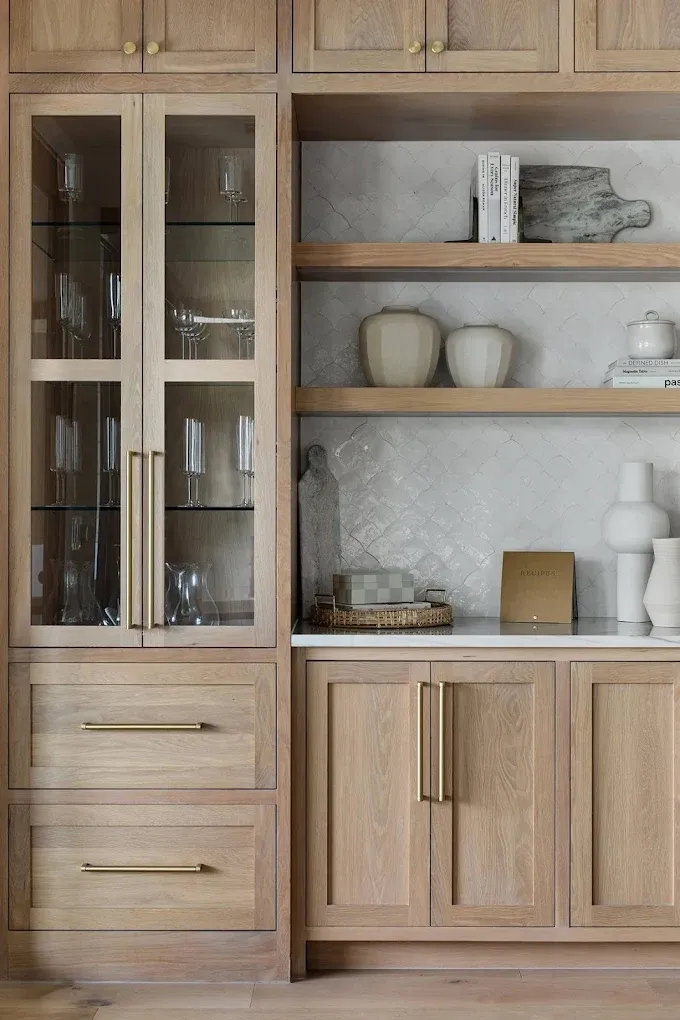 Light wood kitchen cabinetry with glass-front display, open shelves, and gold hardware.