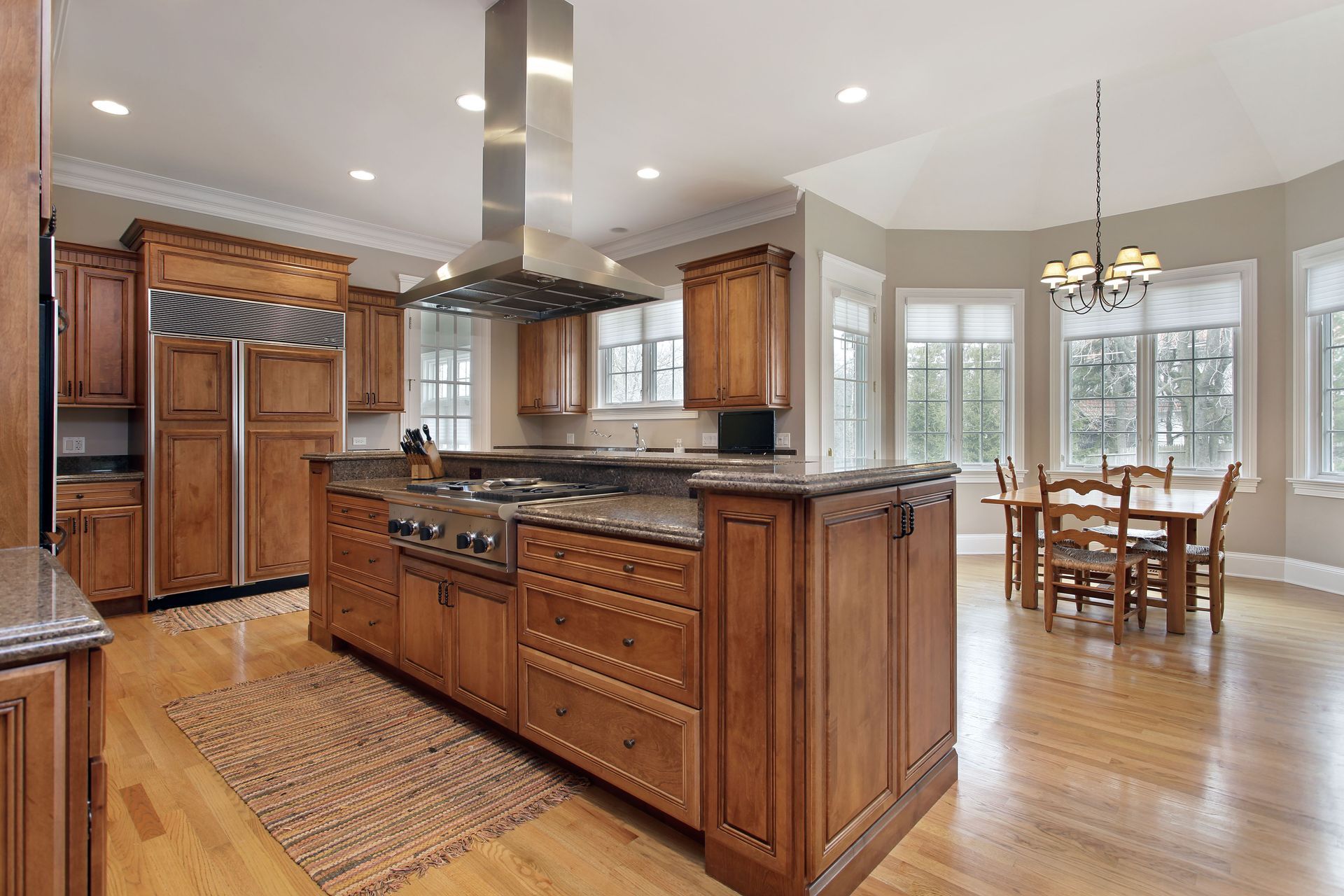Spacious kitchen with wooden cabinets, central island, and adjacent dining area with large windows.