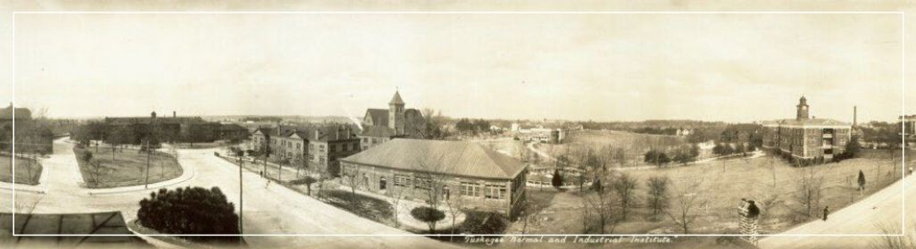 Sepia panoramic view of a historic cityscape with buildings, roads, and towers in the distance