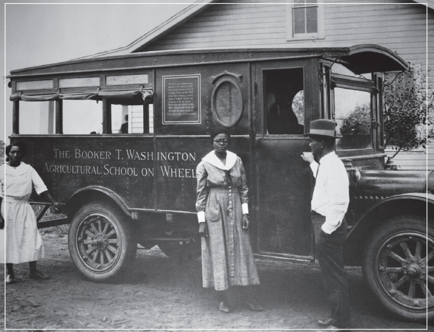Three people stand beside a van labeled “The Booker T. Washington Mutual School on Wheels.”
