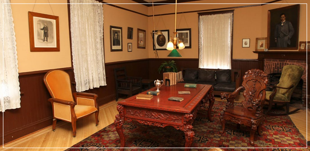 Cozy living room with red carpet, wooden furniture, framed art, and a central coffee table.