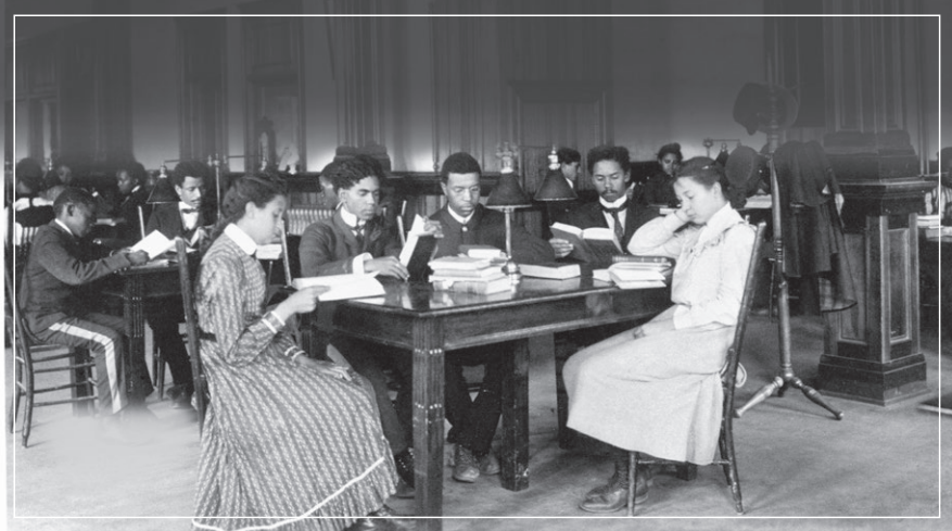 Students seated at desks in a classroom, writing and reading during a lesson