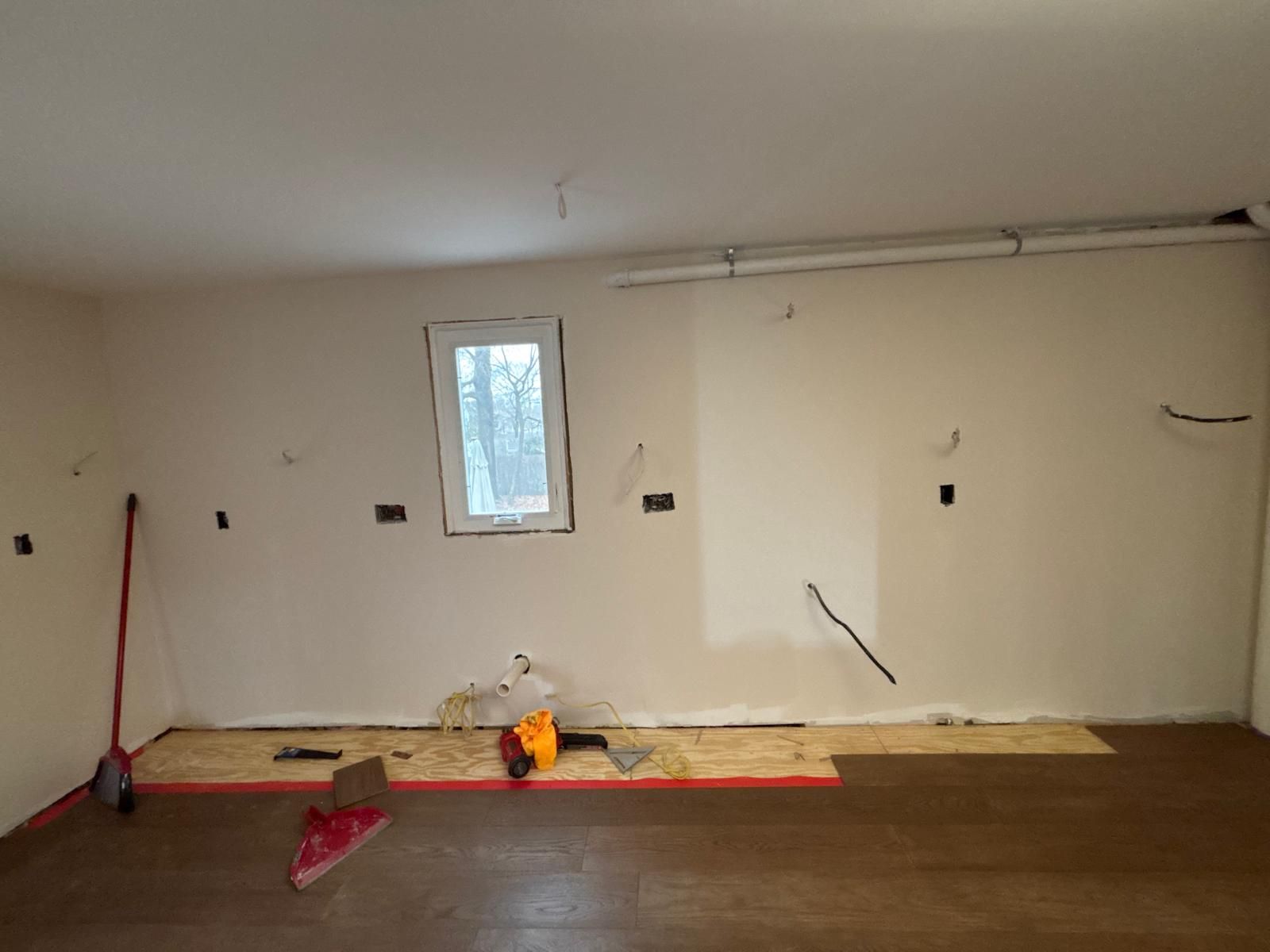 Empty room under renovation with exposed wiring and a small window.