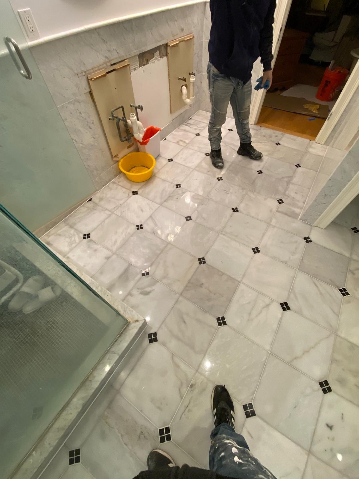 Bathroom floor with patterned marble tiles and two people standing.