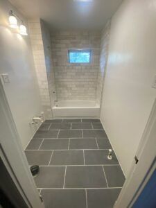 Bathroom with dark tile floor, subway tile shower, and white walls.