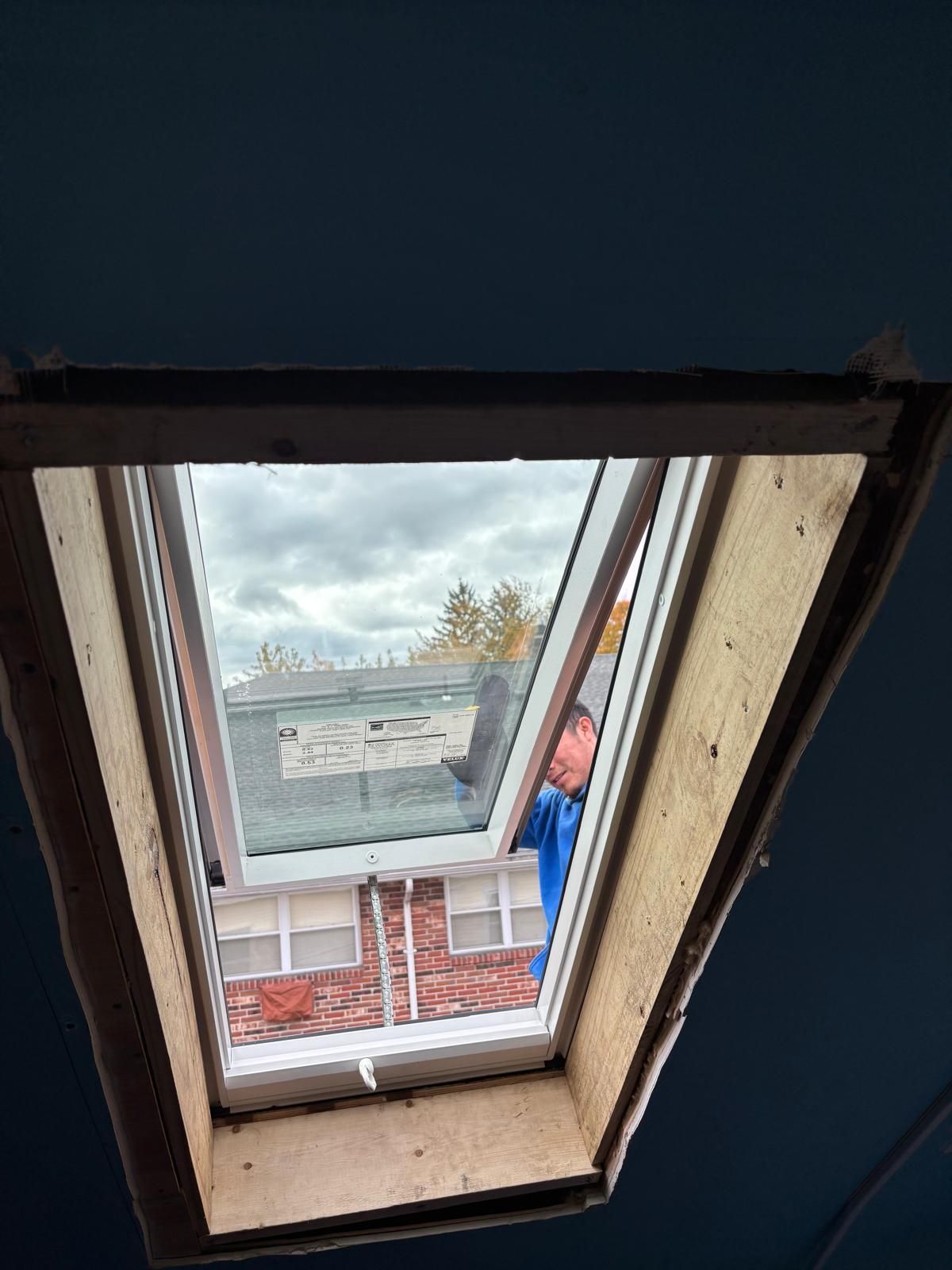 Skylight view of exterior; a person in a blue shirt is visible. Buildings and cloudy sky are seen.