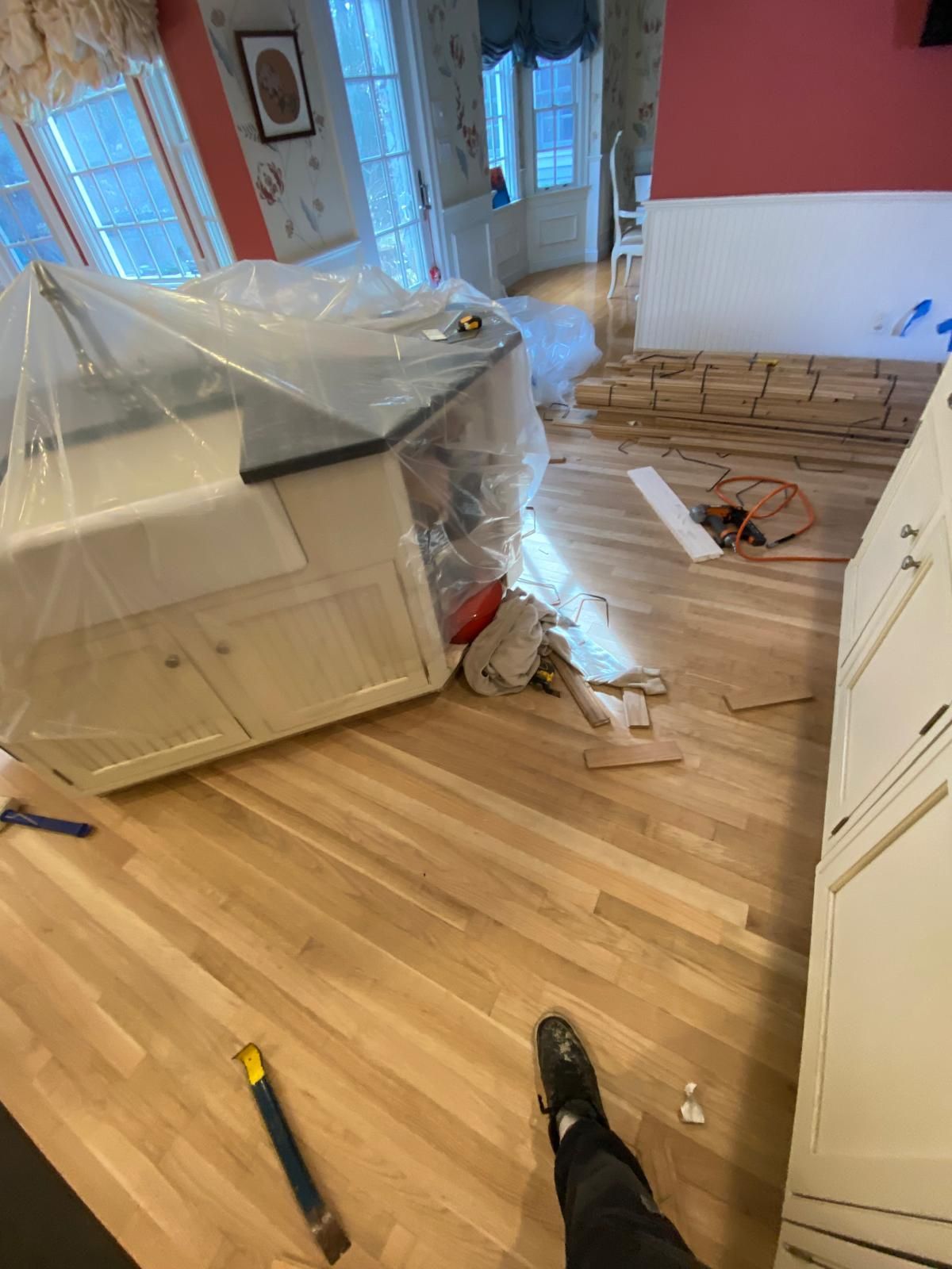 Kitchen undergoing renovation with new wood flooring being installed.