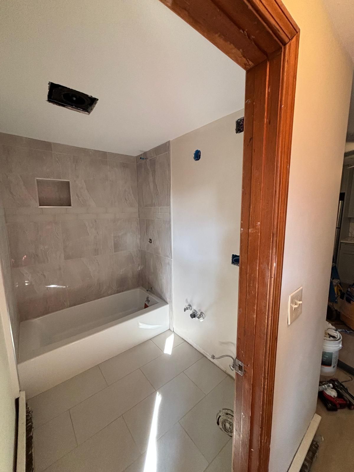 Bathroom renovation with tiled walls, bathtub, and doorway.