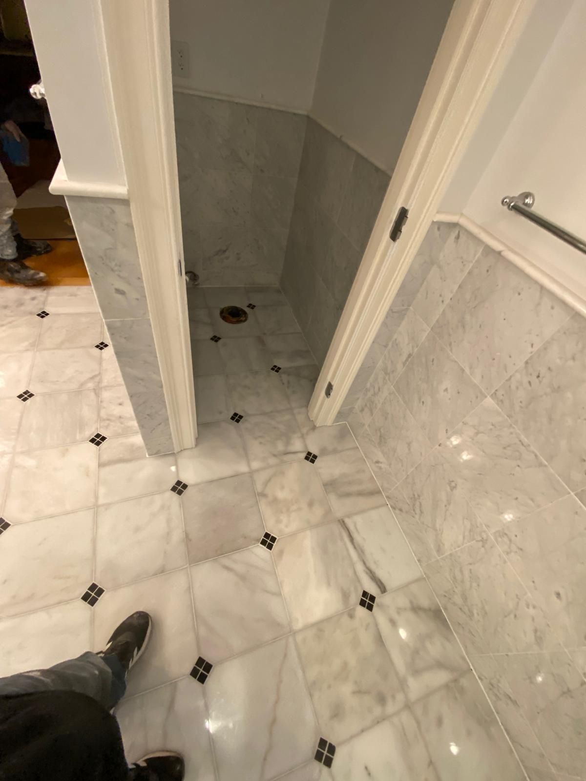 Bathroom with marble floor and walls. Doorway leads to a shower area.
