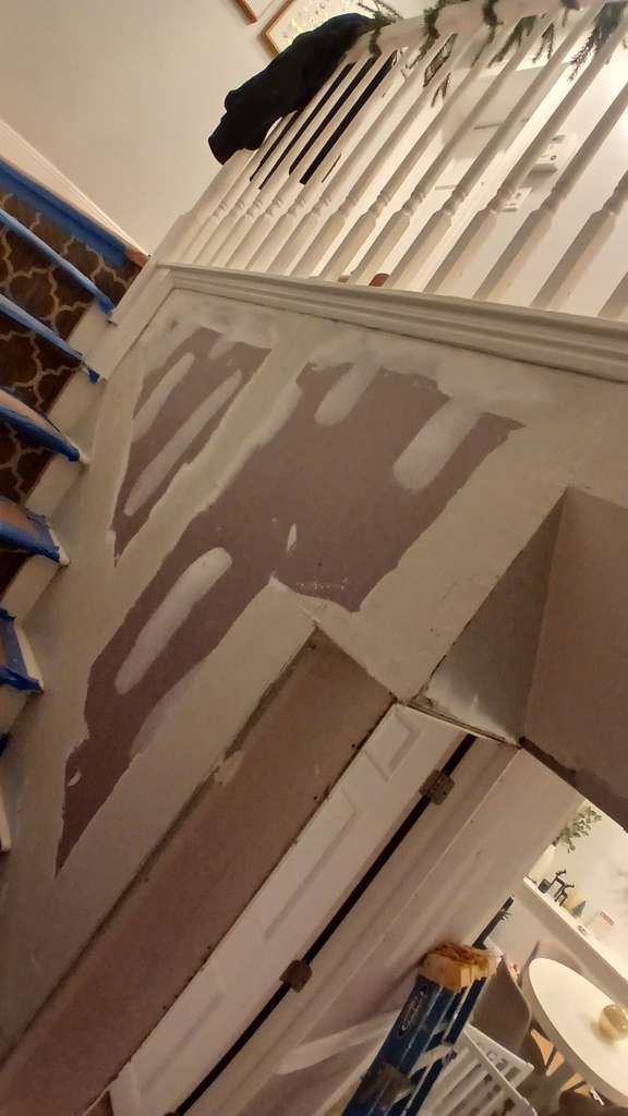 Staircase with sections of wall patched with drywall compound, ready for paint.