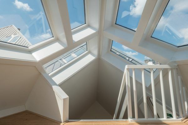 Interior of a room with skylights in a white sloped ceiling, bright blue sky visible.