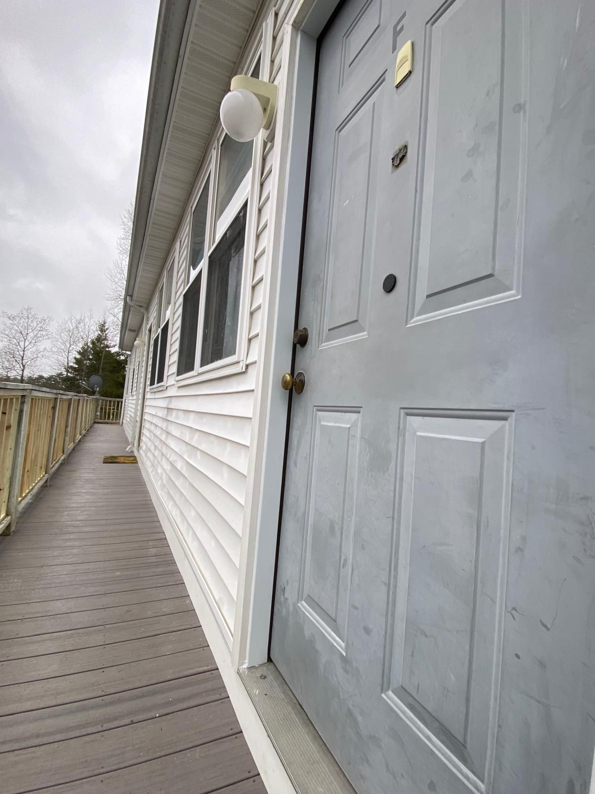 Exterior view of a white building with a gray door and a walkway.