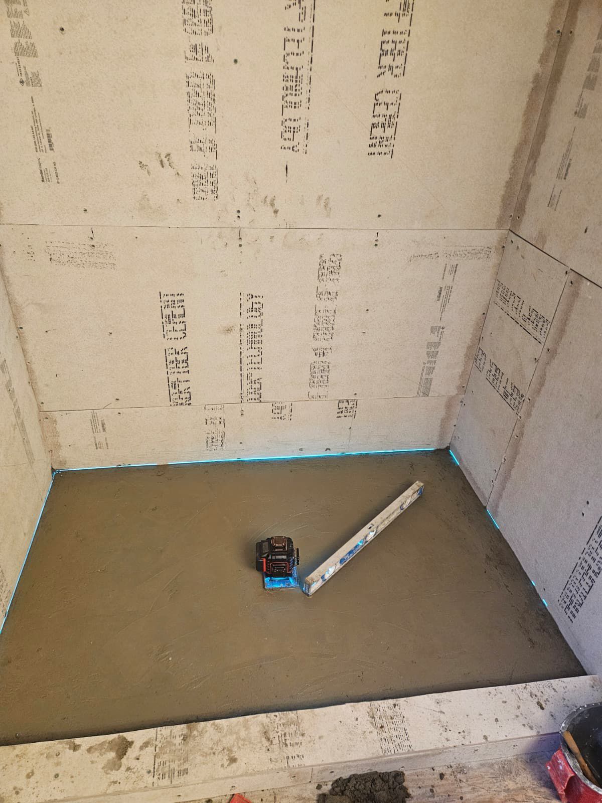 Shower stall with concrete floor, walls, and a level.