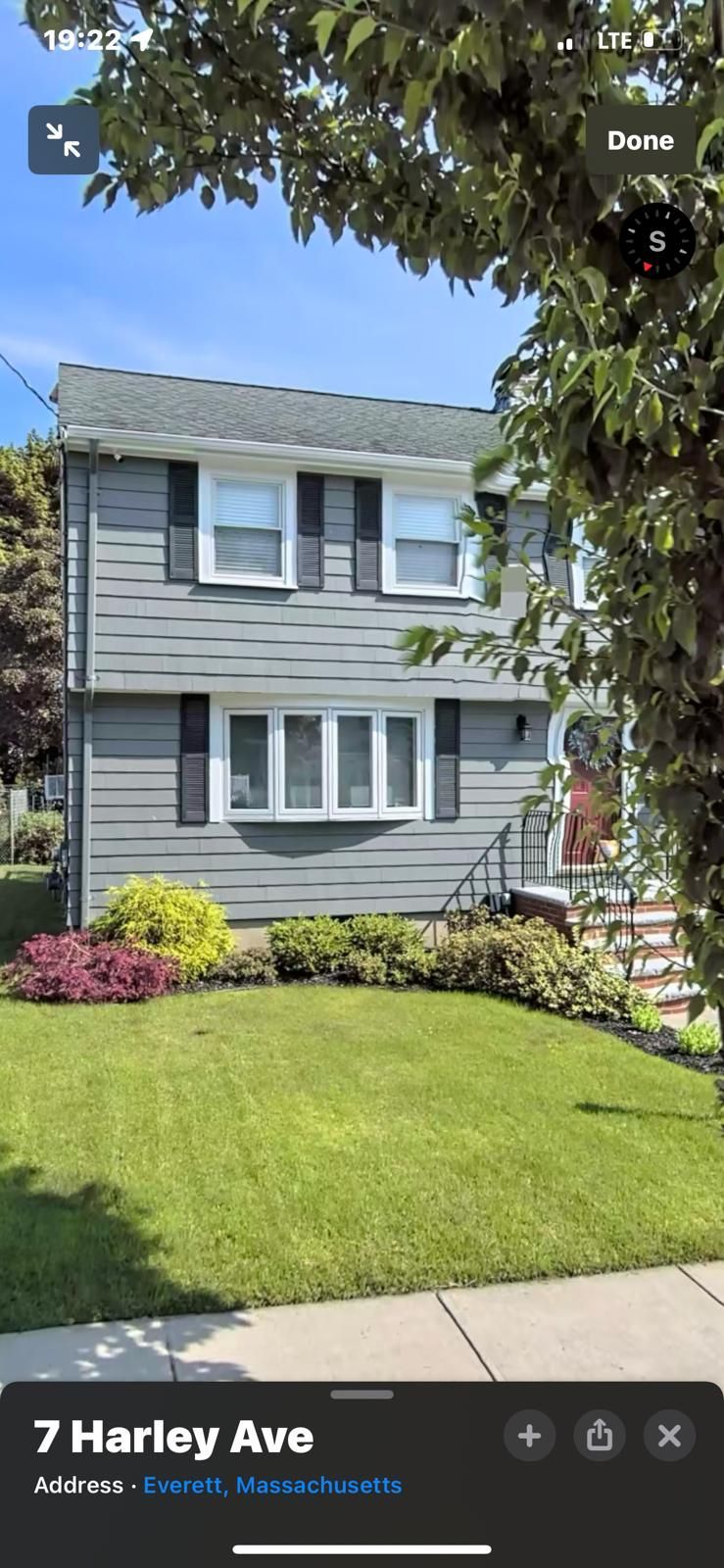 Two-story gray house with black shutters, green lawn, and flowering shrubs at 7 Harley Ave.