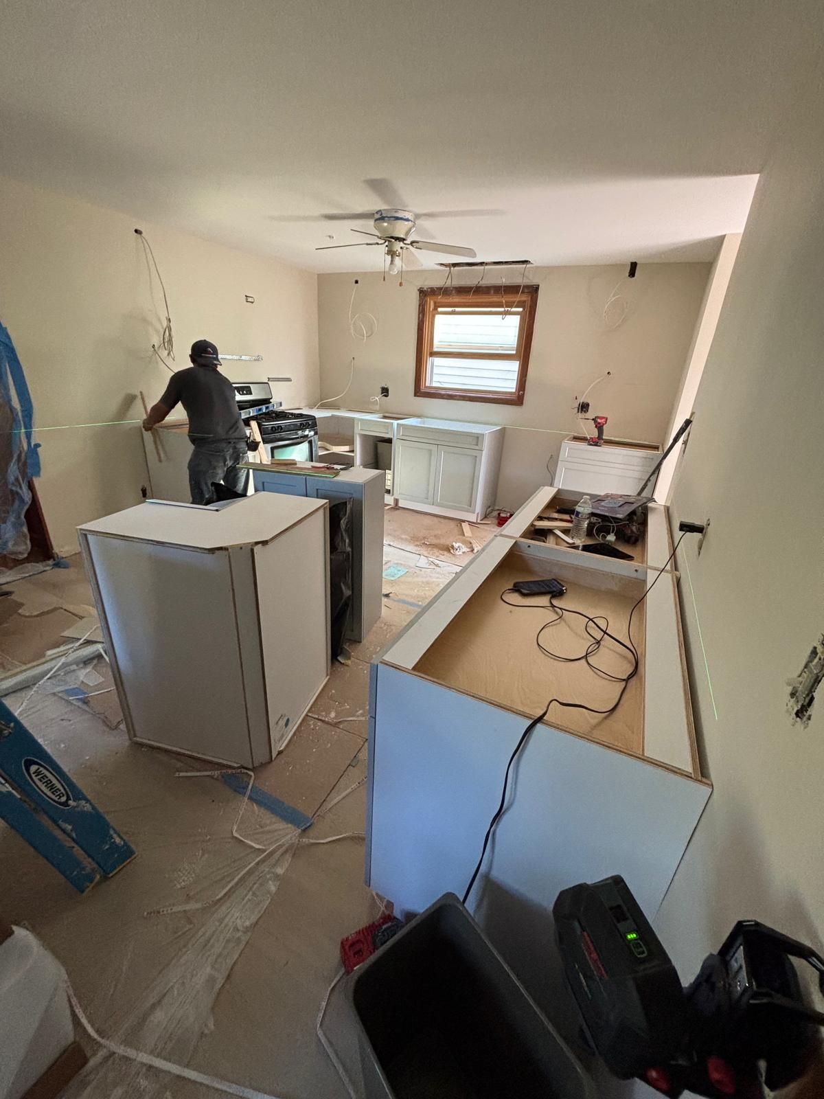 Kitchen under construction with cabinets and a person working inside.