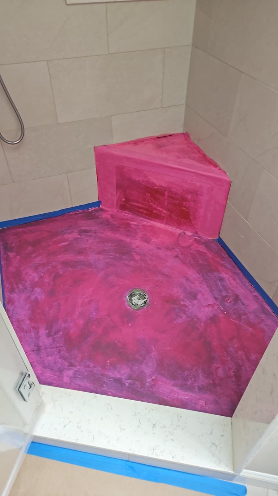 Pink-colored shower floor and bench, with a drain, ready for installation.