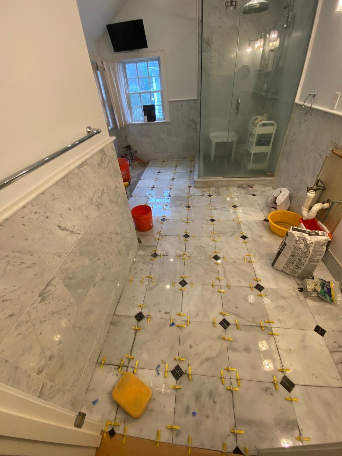 Bathroom floor tiling in progress with white and black patterned tiles.