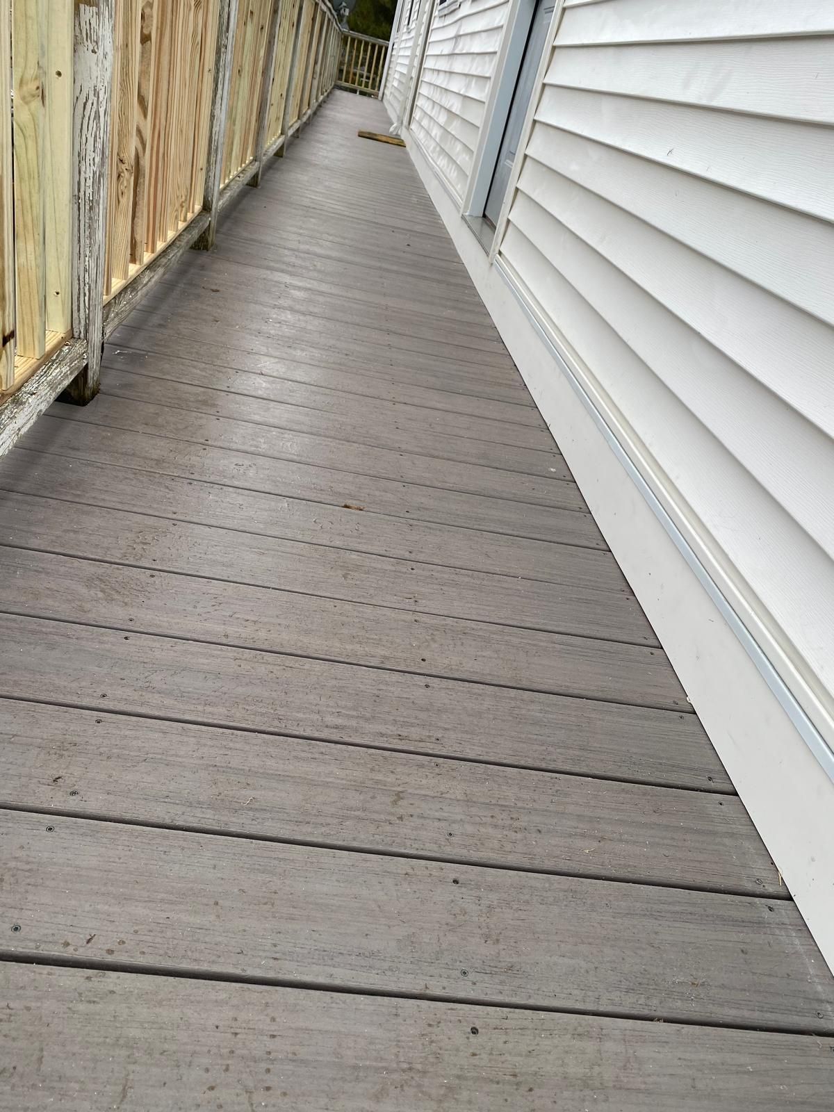 Wooden ramp leading from a building with white siding, alongside a weathered fence.