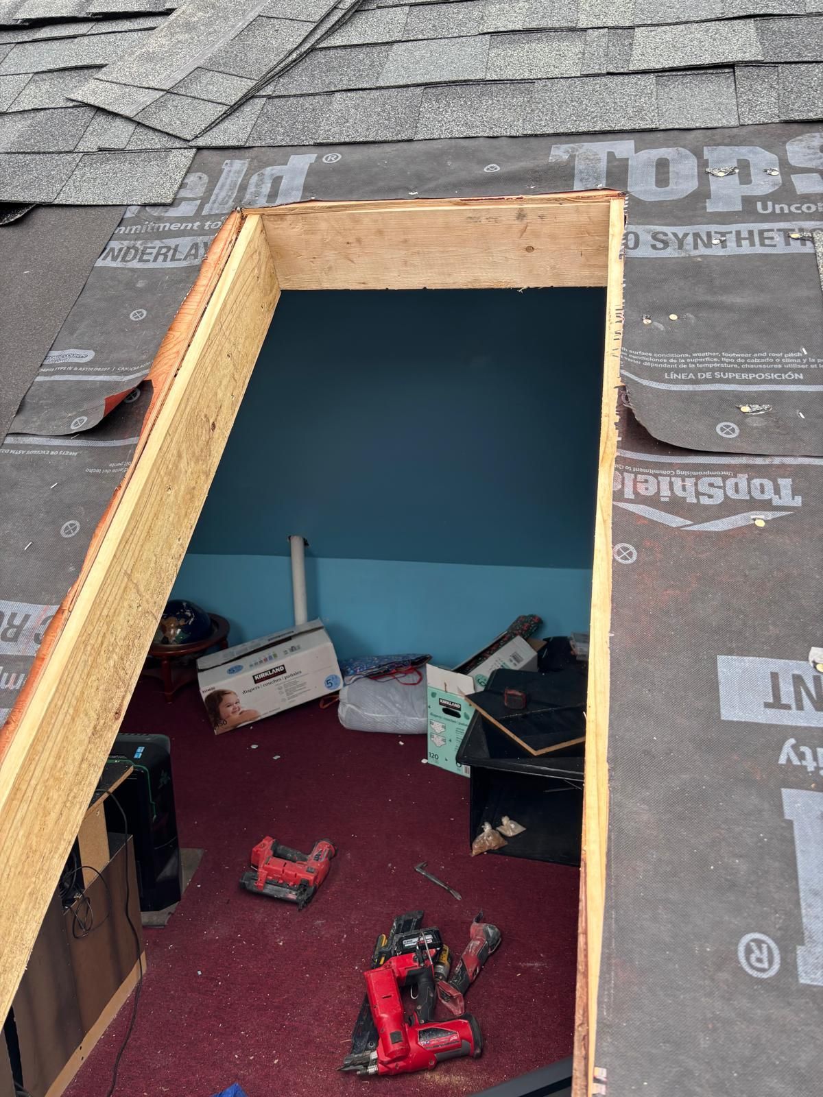 Roof opening with exposed frame; interior room with tools and debris visible.