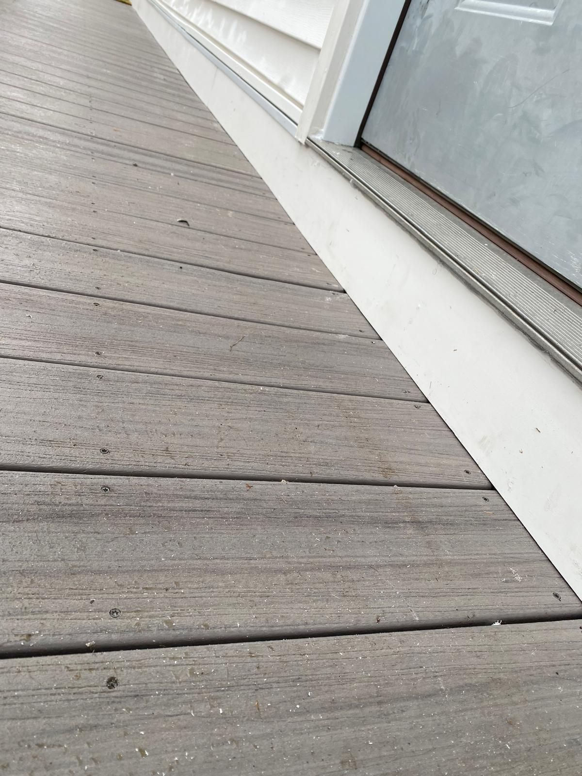 Wooden deck next to a white door frame.