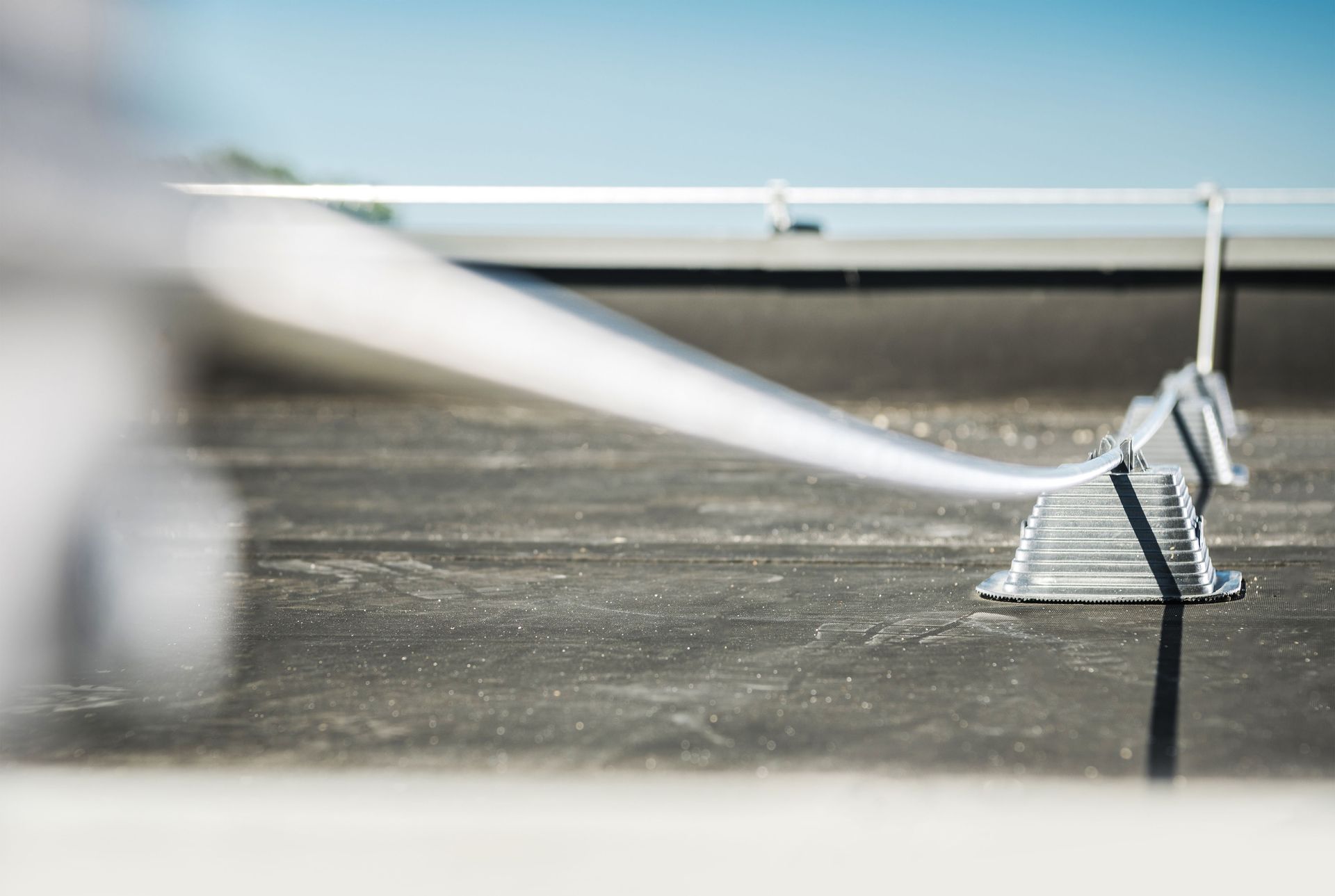 White cable supported by metal stands on a flat rooftop against a blue sky.