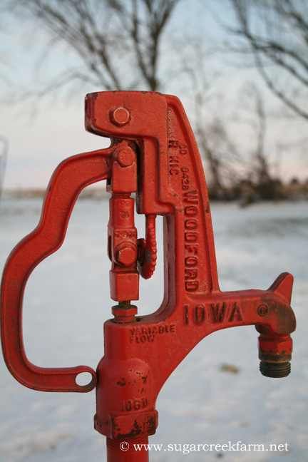 Red hand water pump outdoors with snowy background