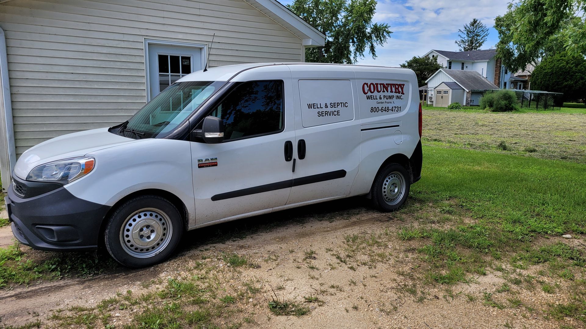 White service van parked beside a house on a grassy driveway, with company logo on the side.