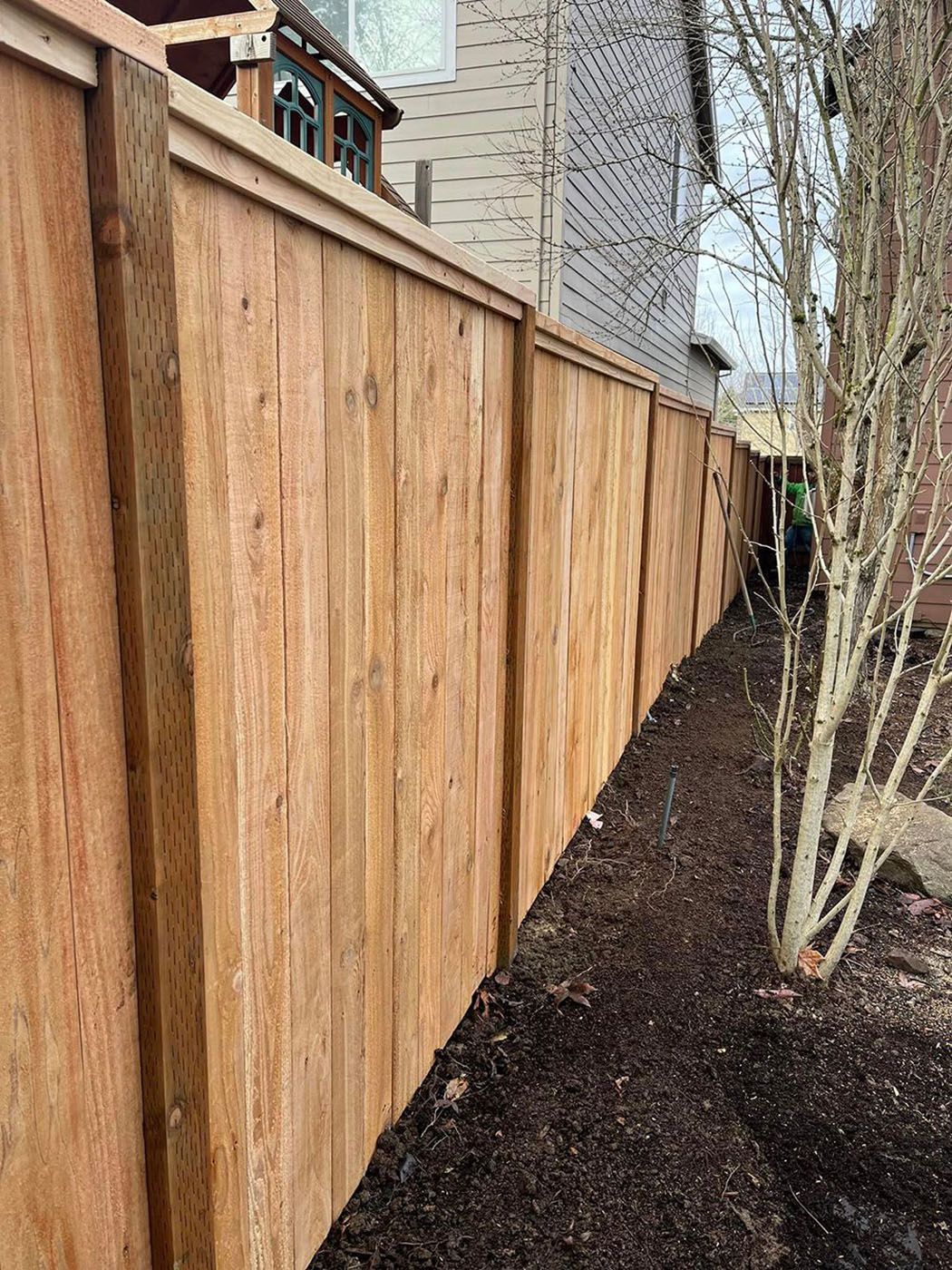 A wooden fence is in the backyard of a house
