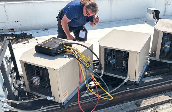 a man is working on a rooftop air conditioner