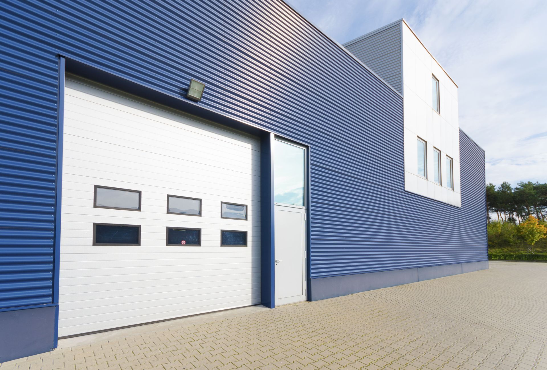 Blue building with silver garage door and a white accent.