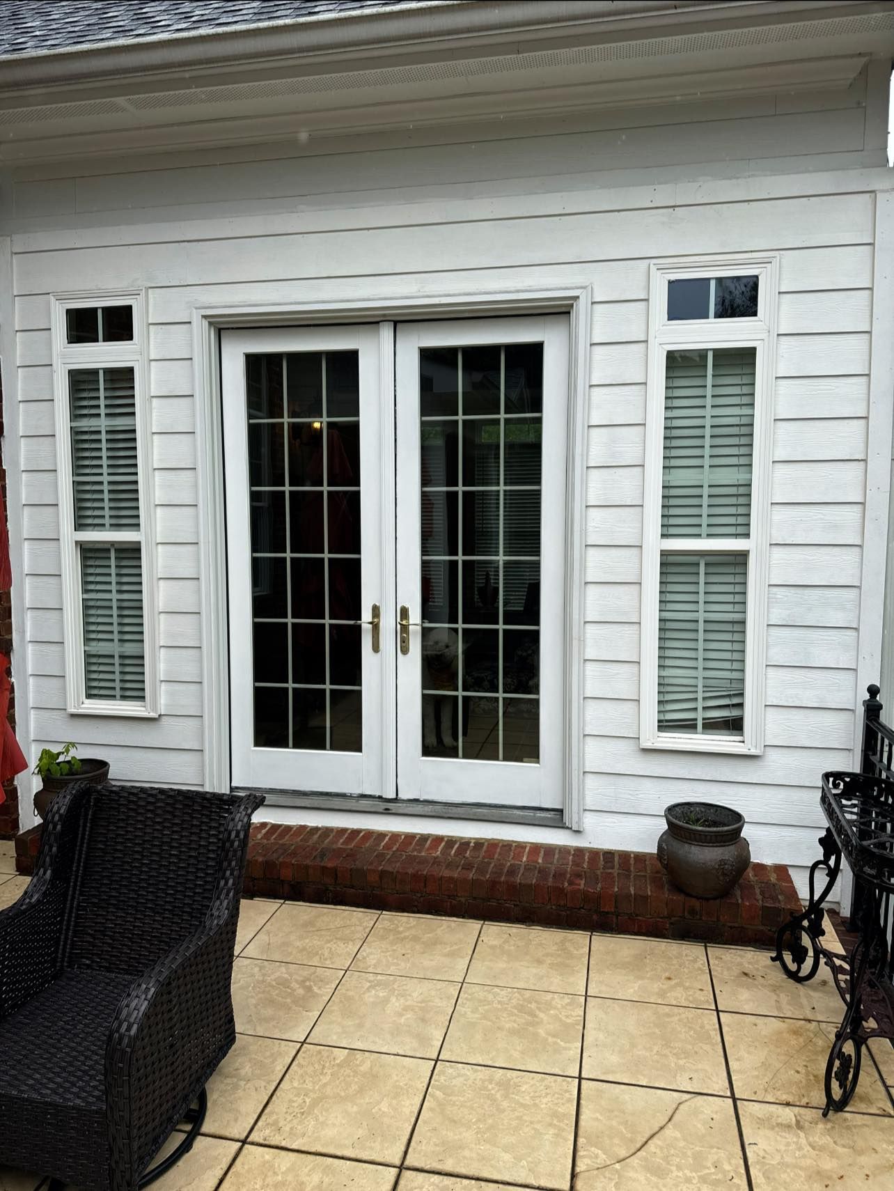 White French doors with sidelight windows, leading to a patio with dark wicker chair.