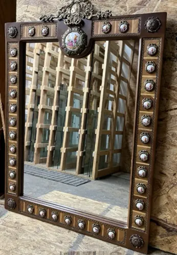 A large mirror with a wooden frame is hanging on a wall.