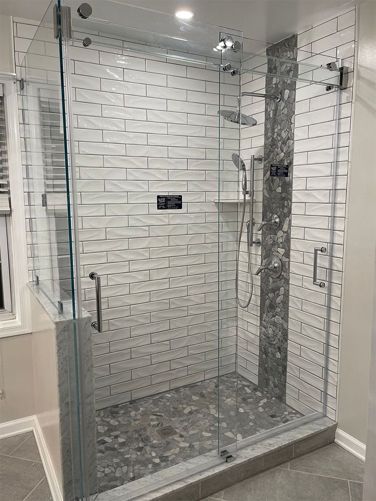 A bathroom with a walk in shower with a glass door.