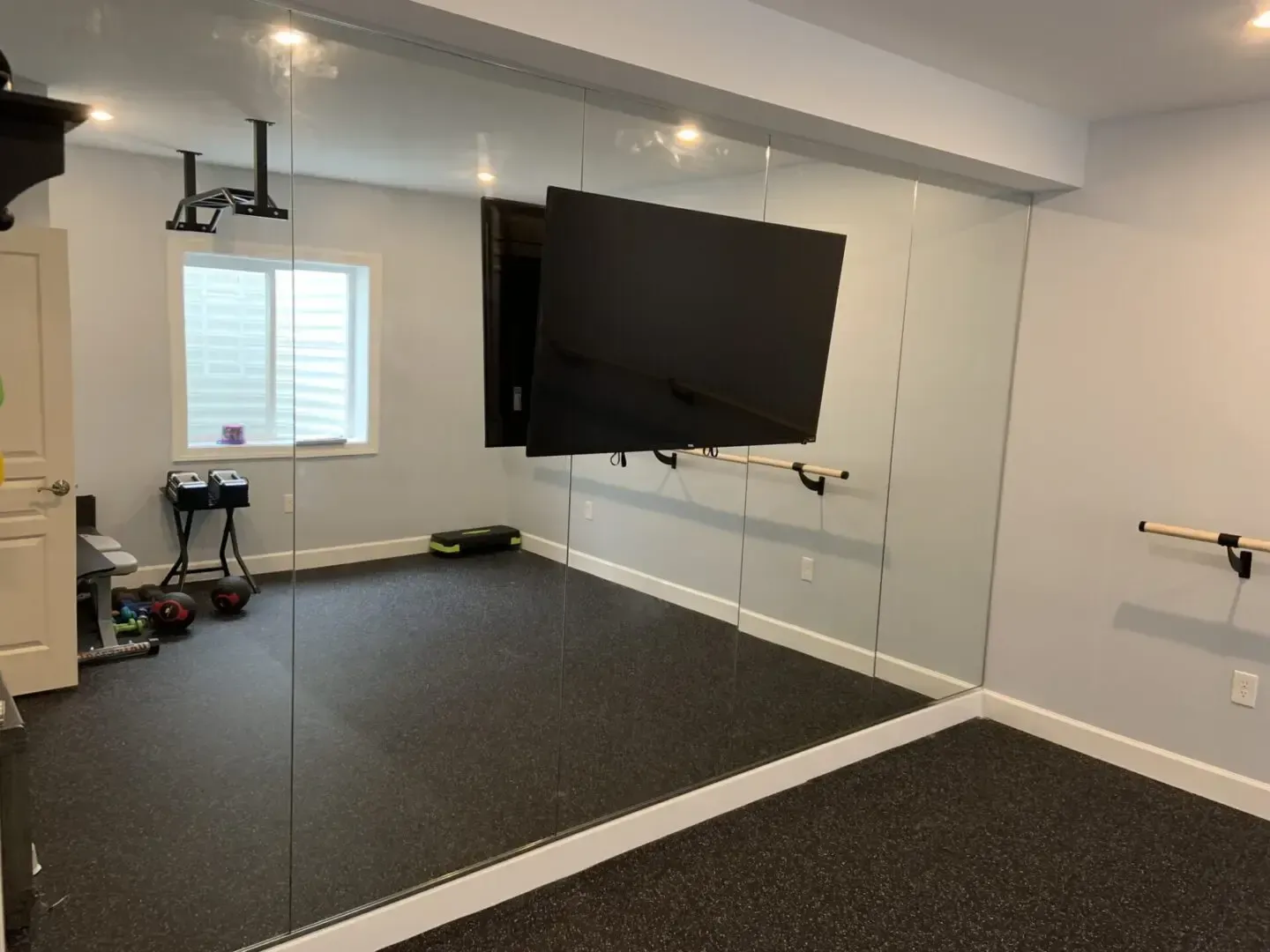 A room with a large mirror and a flat screen tv on the wall.